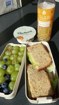 two containers with sandwiches, grapes and yogurt