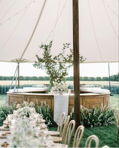 an outdoor tent with tables and chairs set up in the grass for a wedding reception