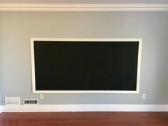 an empty room with hard wood floors and a chalkboard on the wall above it