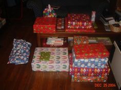 several wrapped presents sitting on the floor in front of a couch and coffee table covered with wrapping paper