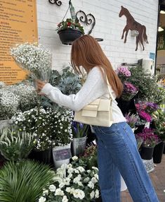 a woman is looking at flowers in the store