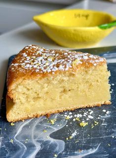 a piece of cake sitting on top of a cutting board next to a yellow bowl