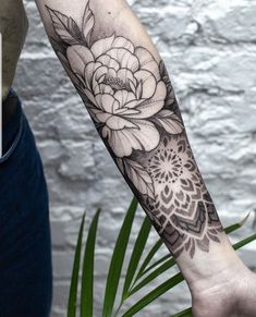 a black and white flower tattoo on the left arm, with an intricate design in the middle