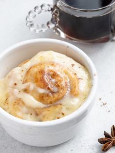 a white bowl filled with food next to a cup of coffee and anisette