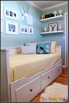 a day bed with drawers underneath it and pictures on the wall behind it in a bedroom