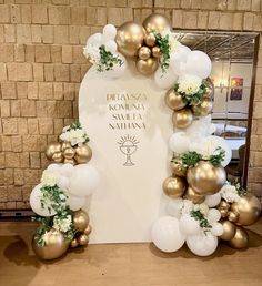 a white and gold balloon arch decorated with flowers