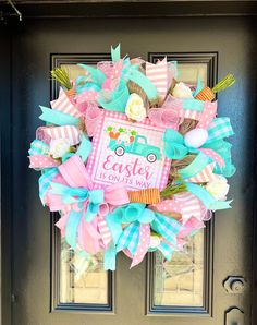 a pink and blue wreath with the words easter is on it's front door