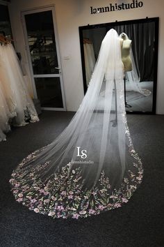 the wedding dress is on display in front of a store window with its veil draped over it