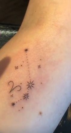 a person with a tattoo on their arm pointing at the stars that are in the sky