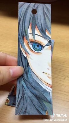 a person holding up a card with an anime character on it's front side