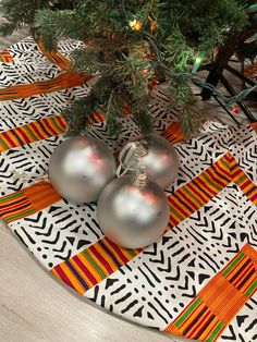 three ornaments sitting on top of a table next to a christmas tree with orange and green ribbons