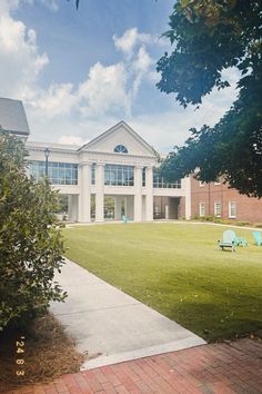 a large building sitting on top of a lush green field next to a park filled with lawn chairs