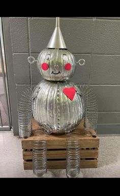 a metal robot sitting on top of a wooden pallet filled with empty cups and cans