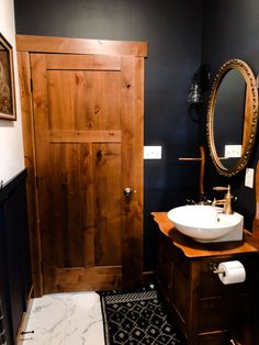 a bathroom with a sink, mirror and wooden door