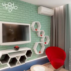 a living room with green brick wall and red chair in front of the flat screen tv