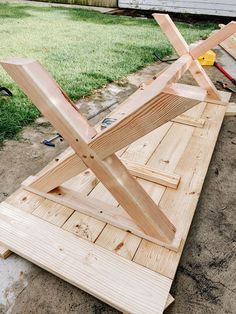 a wooden bench sitting in the middle of a yard next to a building with tools on it