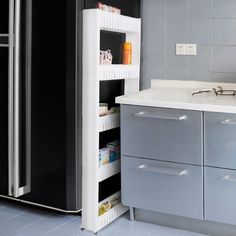 a kitchen with grey cabinets and white counter tops, an open pantry door is in the corner