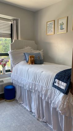 a white bed sitting in a bedroom next to a window with pictures on the wall