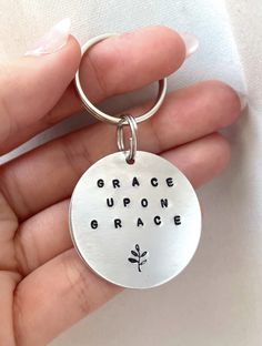 a hand holding a metal keychain with the words grace upon grace on it