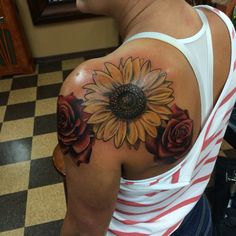 a woman with a sunflower and roses tattoo on her shoulder, in front of a checkered floor