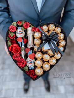 a man in a suit holding a heart shaped box filled with chocolates and roses