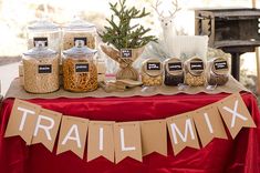 a table topped with jars filled with food next to a sign that says trail mix