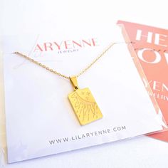 a gold necklace with an angel wing on it sitting next to a magazine and brochure