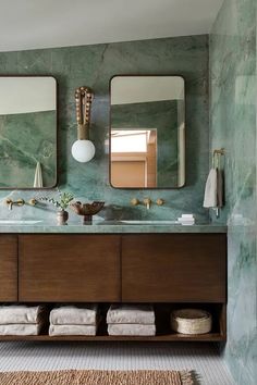 a bathroom with marble counter tops and two mirrors on the wall, along with an area rug