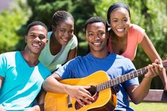 three young people are sitting on a bench and one is holding an acoustic guitar while the other smiles