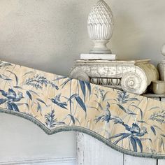 a bed with a blue and white comforter on top of it next to a vase