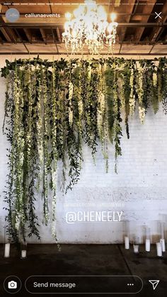 an indoor event with greenery hanging from the ceiling and candles in front of it