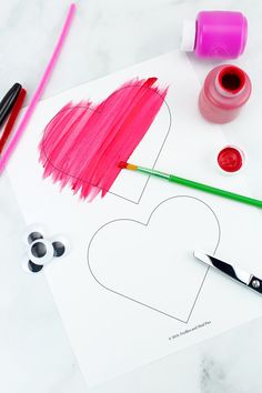 a heart cut out with paint and crayons on the table next to it