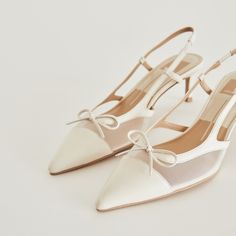 a pair of women's white shoes with bows on the toes and heel straps