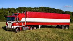 a red and white semi truck parked in a field