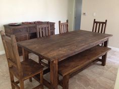 a wooden table and chairs in a room with tile flooring, white walls and wood furniture