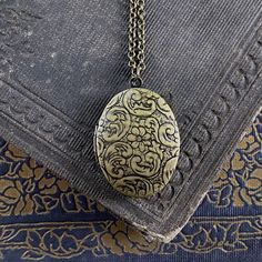 Oval vintage style locket. It is antiqued brass and the inside is quite a bit darker. On 28 inches of antiqued brass chain. Vintage Etched Oval Pendant Locket Necklace, Antique Brass Locket Necklace With Oval Pendant, Vintage Brass Locket Necklace With Oval Pendant, Vintage Charm Oval Pendant Locket Necklace In Brass, Ornate Bronze Locket Necklace With Antique Finish, Bronze Oval Locket Necklace, Bronze Oval Pendant Locket Necklace, Vintage Oval Locket Necklace For Keepsake, Vintage Oval Pendant Locket Necklace With Antique Finish