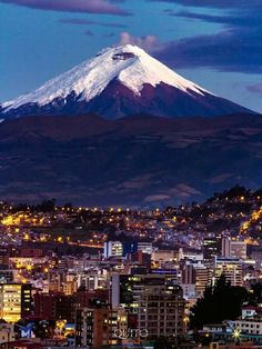 a large mountain towering over a city in the distance at night with lights on it