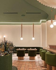 the interior of a modern restaurant with green chairs and round tables in front of them