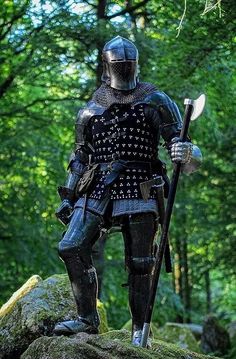 a statue of a man in armor holding a spear and shield on top of a rock