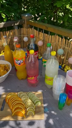 a table topped with drinks and food on top of a wooden table covered in plastic cups