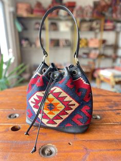 Thank you for visiting our shop!  It's very useful bag as shoulder and as crossbody bag.  This bag is spacious and holds a lot of things. Size         : 30cm x 27cm x 8cm Material  : wool / leather We select beautiful vintage kilims from all over the anatolian area and middle east area. and We do special wash for Kilim rug first, after that cut the kilim to remake unique kilim bags at our atelier  one by one. All products have been produced in a smoke-free environment.  Vintage kilim with colore Bohemian Shoulder Bucket Bag For Shopping, Everyday Bucket Hobo Bag With Detachable Strap, Everyday Use Hobo Bag With Detachable Strap, Everyday Hobo Bag With Detachable Handle In Bucket Shape, Everyday Bucket Shoulder Bag With Detachable Strap, On-the-go Bucket Shoulder Bag, Everyday Bucket Shape Shoulder Bag With Detachable Strap, On-the-go Bucket Shape Shoulder Bag, Bohemian Bucket Bag With Adjustable Strap For Shopping