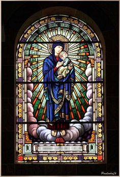 a stained glass window with the image of mary and jesus holding a child in her arms