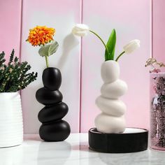 three vases with flowers in them sitting on a table next to some rocks and glitter