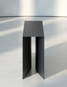 a small black table sitting on top of a white floor in front of a wall