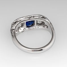 This lovely circa 1930s antique sapphire ring is centered with one (1), bead set, oval cut natural blue sapphire weighing 0.81 carats and flanked to each side by one (1), bead set, old European cut diamond. The shoulders of the ring are each bead set with two (2) round single cut diamonds. The gemstones are bordered with milgrain edging. Engraved details accent the side faces of the ring. The ring measures 7.3mm at the top, rises 3.7mm above the finger, tapering to 2.9mm wide and 1.6mm thick at the base of the shank. The ring is currently a size 6 and we offer complimentary resizing to fit. Classic Oval Sapphire Ring With Polished Finish, Classic Oval Sapphire Ring, Classic Oval Cabochon Sapphire Ring With Bezel Setting, Classic Sapphire Ring With Oval Cabochon Bezel Setting, Elegant Sapphire Signet Ring, Classic Sapphire Ring Oval Cabochon, Classic Blue Sapphire Ring In 14k White Gold, Timeless Hallmarked Sapphire Ring, Classic Sapphire Birthstone Ring