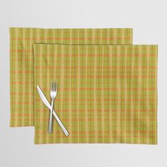 two place mats with forks and spoons on them, one green checkered cloth