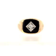 A gent's black onyx and diamond ring.  Set in the center of the ring is a bezel set rectangular cabochon black onyx.  Set in the center of the onyx in a kite shaped illusion plate is a round brilliant cut diamond. This ring is a size 12 and cannot be sized by our goldsmith. Stone Information Type: Black Onyx Type: Natural Diamond -  Clarity: SI1 Color: H Cuts: Round Brilliant Cut Total Carats: 0.051 carat calculated Metal Content Guaranteed 10k yellow gold Weight: 10.0 grams Measurements of Ring Black Rectangular Signet Ring For Anniversary, Black Ring With Single Diamond In Fine Jewelry Style, Black Ring With Single Diamond, Classic Black Ring With Single Diamond, Formal Black Ring With Single Diamond, Classic Black Diamond Ring Stamped 14k, Classic Black Jewelry With Single Diamond, Classic Black Signet Ring, Yellow Gold Mens Rings