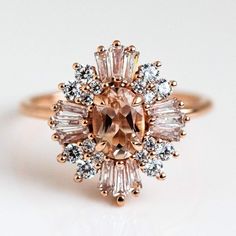 an engagement ring with pink and white stones on it's center, surrounded by small diamonds