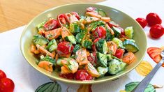 a bowl filled with cucumbers and tomatoes on top of a table