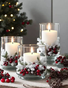 three candles are sitting on a table with holly wreaths and pine cones around them